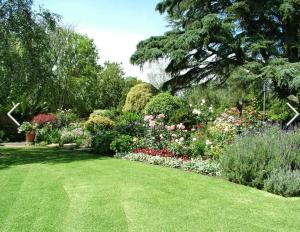 a garden with a green lawn and flowers at Bedford Way cottages in Bedford