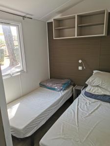 Duas camas num pequeno quarto com uma janela em Les Genêts Valderois em Valderiès