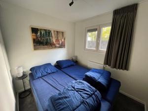 a bedroom with two blue beds and a window at Camping de Vinkenkamp in Lieren