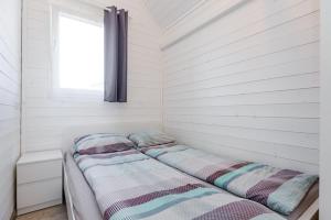 2 Betten in einem weißen Zimmer mit Fenster in der Unterkunft Audronašų Vilos in Šventoji