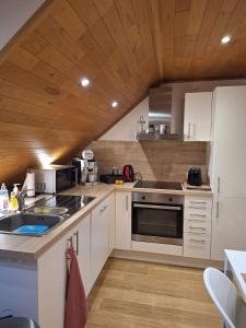 cocina con armarios blancos y techo de madera en Gite L'Ecureuil Namur Wépion- Appartement 4 personnes, en Namur