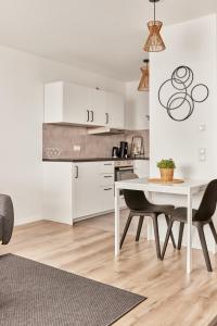 a kitchen with white cabinets and a table and chairs at Elegantes 1 Zimmer Apartment Neubau in Mannheim