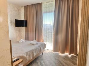 1 dormitorio con cama y ventana grande en Green Cape Tower en Batumi
