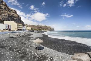 a beach with an umbrella and the ocean at Bonita Apto Nieves in Playa de Santiago