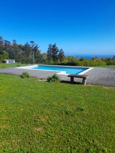 a swimming pool with a bench in the grass at Casas do Forneiro O Horizonte T2 in Nordeste