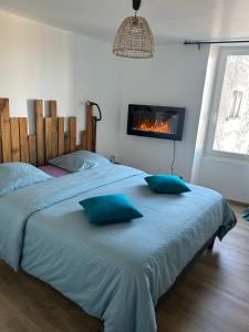 Chez Romain et Saphie في ليه بو دو بروفنس: غرفة نوم مع سرير ووسائد زرقاء ومدفأة