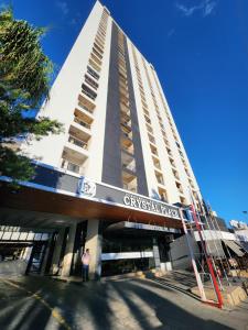 a man standing in front of a tall building at Flat Apart Hotel Crystal Place in Goiânia