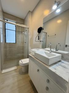a bathroom with a sink and a toilet and a mirror at Gontijo Apart Hotel in Itajubá +22 photos