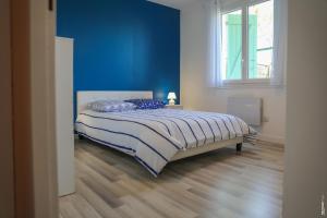 une chambre avec un lit avec un mur bleu dans l'établissement JOLIE MAISON - CALME - JARDIN - GAILLAC, à Gaillac