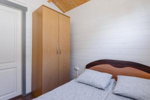 1 dormitorio con 1 cama y armario de madera en Nameliai Penkios gulbės, en Šventoji