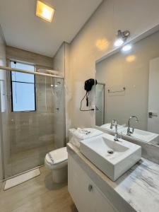 W łazience znajduje się umywalka, toaleta i lustro. w obiekcie Gontijo Apart Hotel w mieście Itajubá