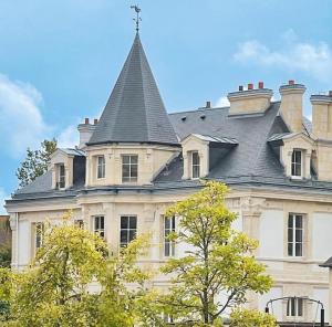 a large white building with a gray roof at WeLiving in Caen