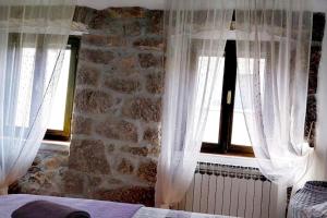 a bedroom with white curtains and a stone wall at Historic Stone House KATI Perfect Family Retreat With Garden BBQ And Picturesque Landscapes in Ledenice