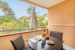einen Tisch und Stühle mit Sonnenschirm auf dem Balkon in der Unterkunft Résidence Pierre & Vacances L’Anse De Pramousquier in Le Lavandou