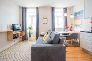 ein Wohnzimmer mit einem blauen Sofa und einer Küche in der Unterkunft GuestReady - Chic and vibrant stay near Anjos in Lissabon