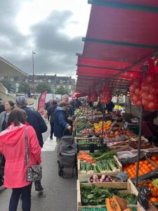 a group of people walking around a market with produce at Appartement charmant et confortable en centre-ville in Condé-sur-Noireau