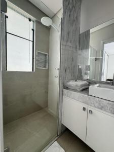 ein Bad mit einer Dusche und einem Waschbecken in der Unterkunft Gontijo Apart Hotel in Itajubá