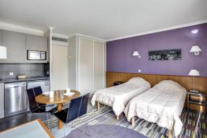 two beds in a room with a table and a kitchen at GuestReady - Studio near Porte de Versailles Metro in Issy-les-Moulineaux
