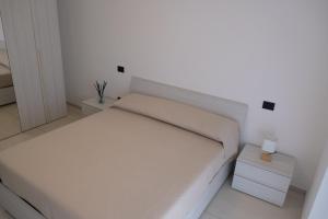 Un dormitorio blanco con una cama y una mesita de noche. en Casa Nuvola, en Vietri