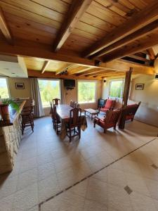 sala de estar con techo de madera, mesa y sillas en Cabañas Terra, en Lago Puelo