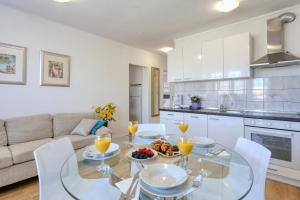 cocina y sala de estar con mesa de cristal y sillas en Apartment Ivica, en Zadar