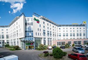 een groot wit gebouw met auto's geparkeerd op een parkeerplaats bij Best Western Conference Airporthotel Frankfurt Mörfelden in Mörfelden-Walldorf