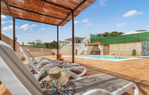 a child sitting on a deck chair next to a swimming pool at 2 Bedroom Gorgeous Home In El Morche in Morche