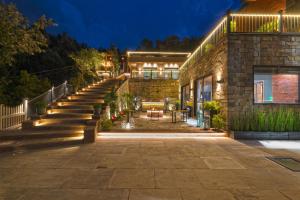a stone house with a patio at night at SaffronStays Aruunoday - 4BR with Theatre, Deck & Bonfire in Bhīm Tāl