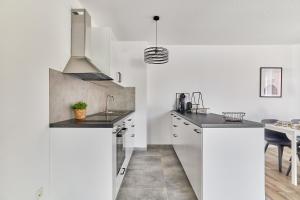 a kitchen with white cabinets and a sink and a table at Neubau Luxus Penthouse - Netflix - BBQ in Mannheim