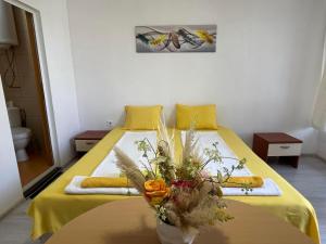 a bedroom with a bed with a vase of flowers on it at Къща Поморини Несебър in Nesebar
