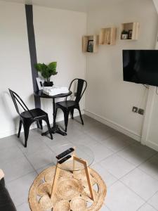 ein Wohnzimmer mit einem TV, einem Tisch und Stühlen in der Unterkunft Coeur de Bastide in Bordeaux
