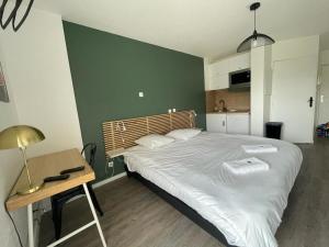 1 dormitorio con 1 cama grande, mesa y escritorio en Bel appartement design tout confort (Parking Gratuit) à 10 minutes de Bordeaux, en Cenon