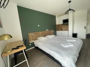 a bedroom with a large bed and a table and a desk at Bel appartement design tout confort (Parking Gratuit) à 10 minutes de Bordeaux in Cenon