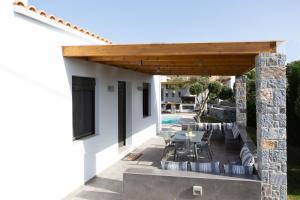 a patio with a table and chairs under a wooden pergola at Villa Stavelia in Gouves