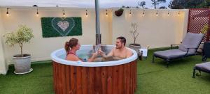 um homem e uma mulher sentados numa banheira de hidromassagem em Riversong Guest House na Cidade do Cabo