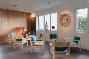 ein Wartezimmer mit Tischen, Stühlen und einem Spiegel in der Unterkunft Hôtel & Spa Le Grand Large in Dolus d'Oléron