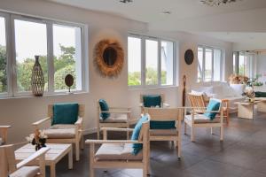 a salon with chairs and tables and windows at Hôtel & Spa Le Grand Large in Dolus d'Oléron