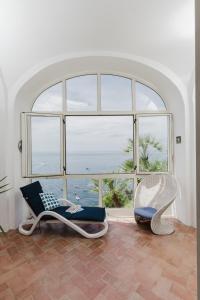 ポジターノにあるLa Casa del bluの椅子2脚と大きな窓が備わる客室です。
