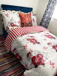 - un lit avec des draps et des oreillers rouges et blancs dans l'établissement Shepherds House - 3 Bedroom, à Goodmayes