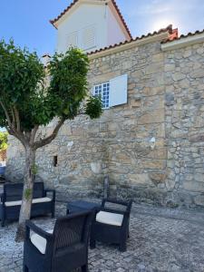 een stenen muur met twee stoelen en een boom bij Stone House in Salzedas
