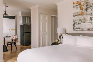 a white bedroom with a large bed and a kitchen at Sonder The Sunset in Vancouver