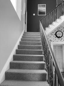 a staircase in a house with a clock on the wall at Laston House in Ilfracombe