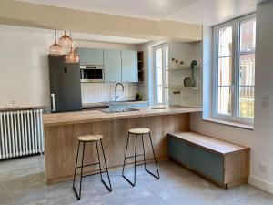 a kitchen with two stools and a counter in a room at Maison Fleurs de bobo in Les Minières
