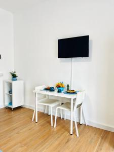 ソレントにあるAzzurrissima Home-B&b Sorrento centroの白いテーブル(椅子付)、壁掛けテレビ