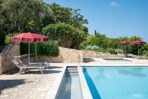 a swimming pool with two chairs and an umbrella at La Muccheria in San Vincenzo