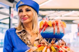 una mujer parada en una tienda sosteniendo una muestra de comida en Essential Suite B&B Botanic en Nápoles
