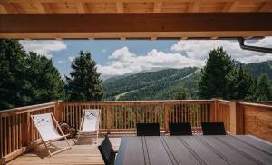 eine Terrasse mit Stühlen und einem Tisch mit Aussicht in der Unterkunft Chalet Sunnseitn - auf der Turracher Höhe in Turracher Hohe