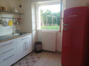 a kitchen with a red refrigerator in front of a window at La maison au bord de l'eau in Graçay