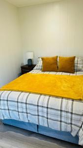 1 dormitorio con 1 cama con manta amarilla en Couston Lakes Resorts, en Bathgate