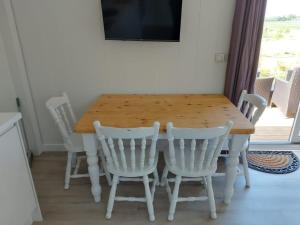 a wooden table with four white chairs around it at Couston Lakes Resorts in Bathgate